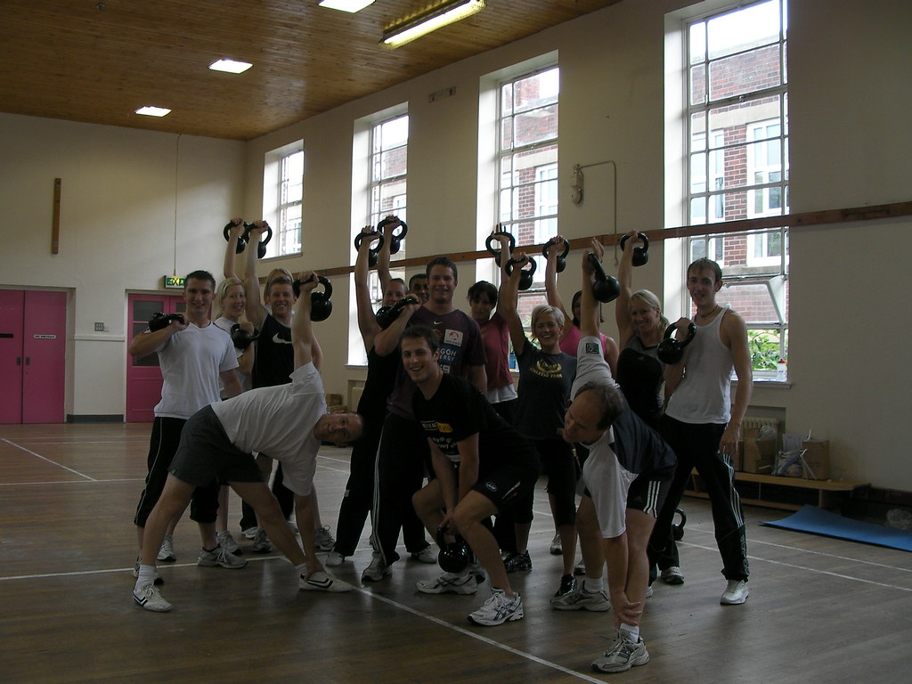 Group of people of various ages and fitness levels holding kettlebells, showcasing the versatility of kettlebell workouts.