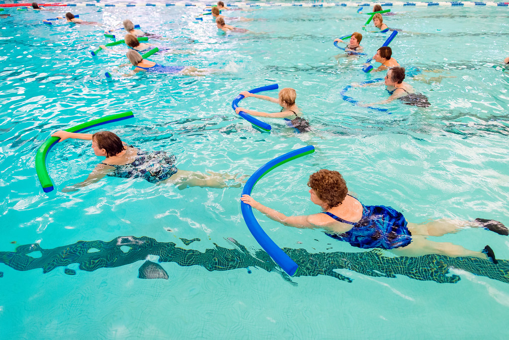 A diverse group of people participating in various aquatic fitness activities in a pool.