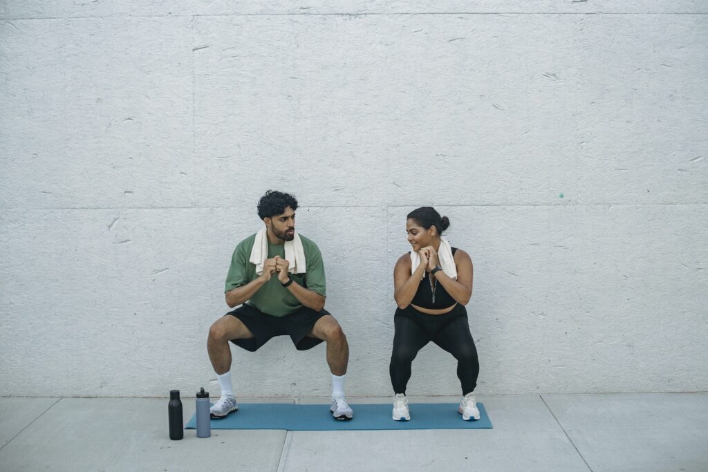 Person performing a wall sit exercise against a white wall