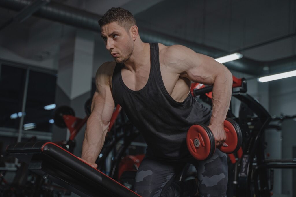 A man in athletic gear performing a dumbell kickback exercise to target his tricep muscles