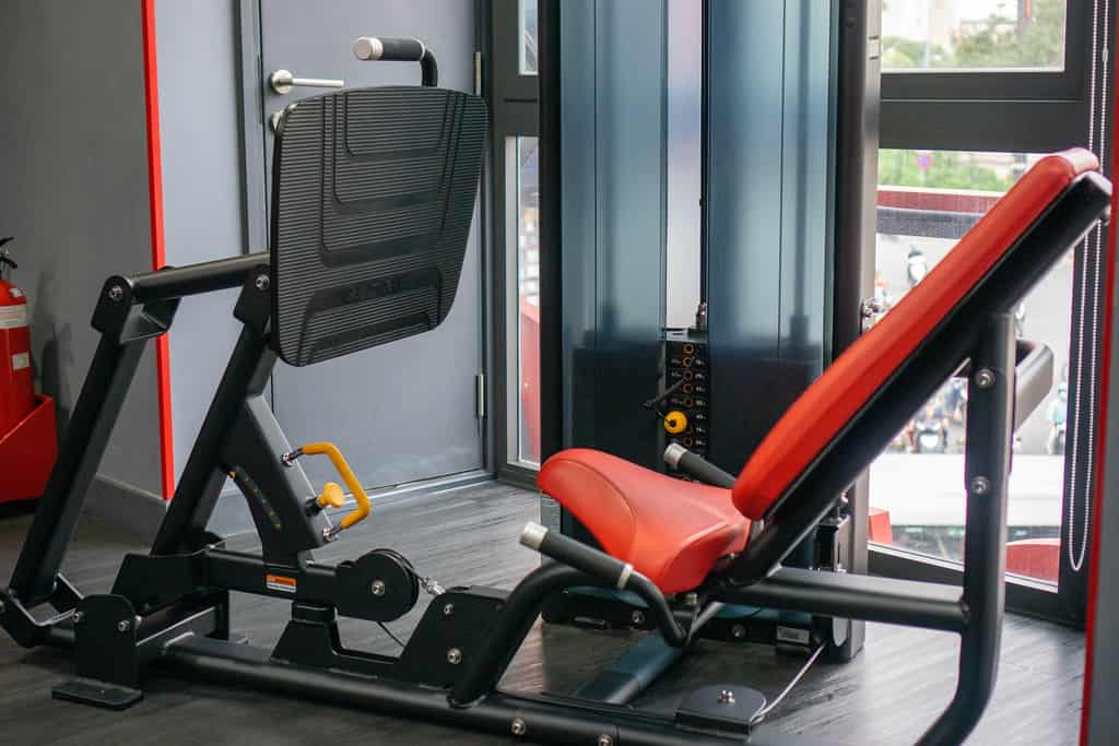 Adjustable leg press machine with incline seat in a well-lit gym room