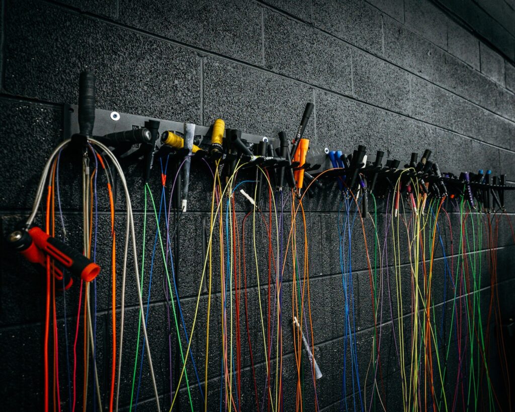 Colorful jump ropes coiled neatly on a wooden gym floor, ready for Crossfit training.