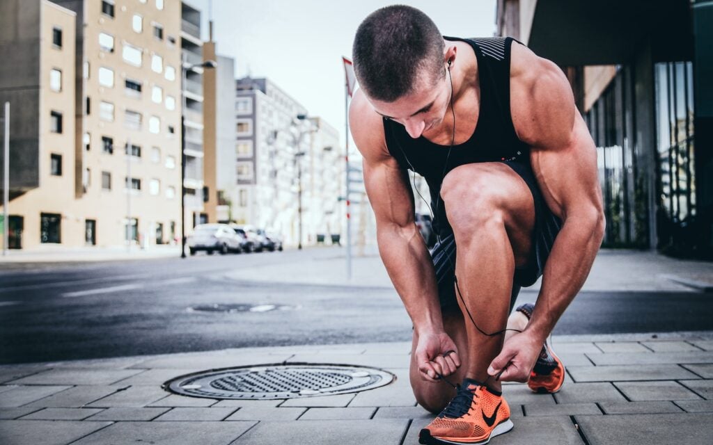 Beginner runner tying shoelaces at sunrise in a park.