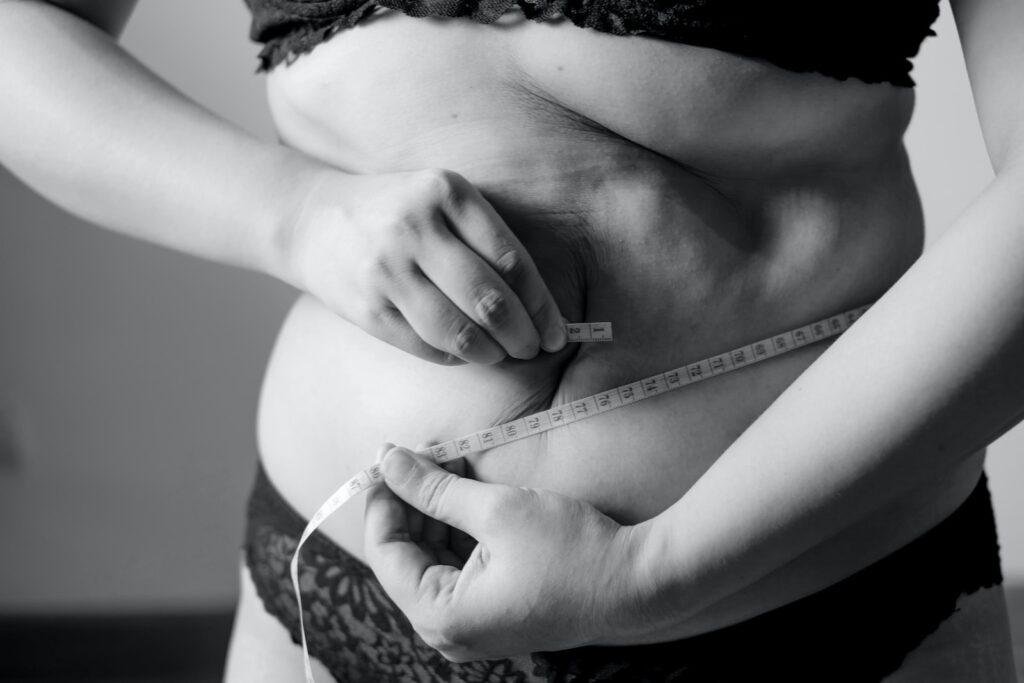 Woman measuring her waist with a tape measure for weight loss