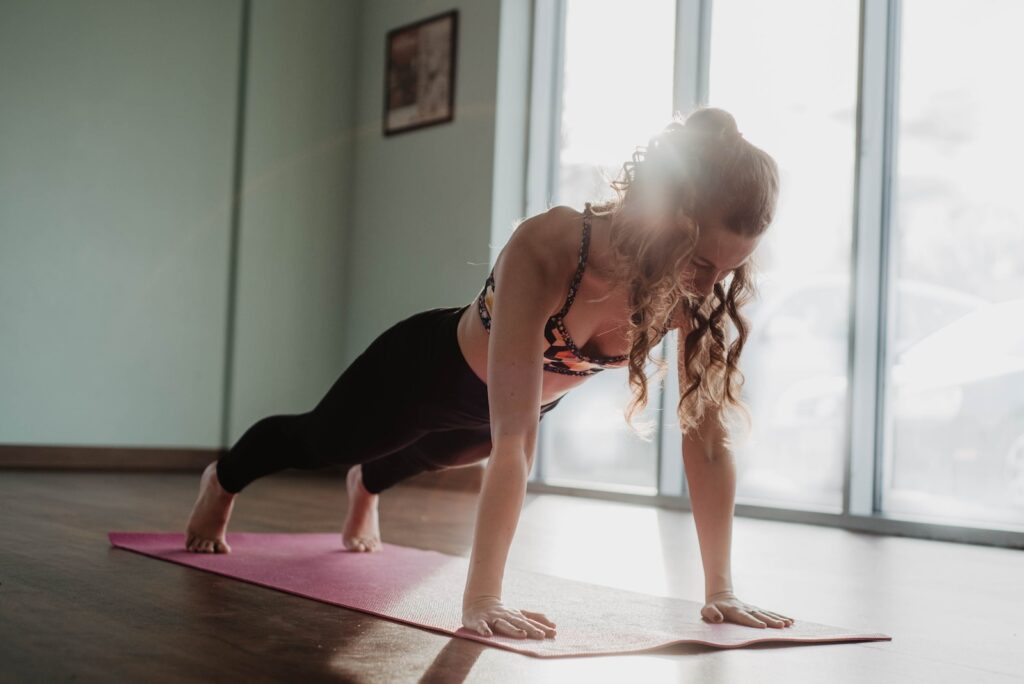 A fit woman in athletic wear holding a plank position on a yoga mat.