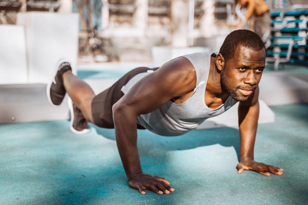 Man demonstrating perfect push-up form in a gym setting, showcasing the technique required for mastering push-ups.