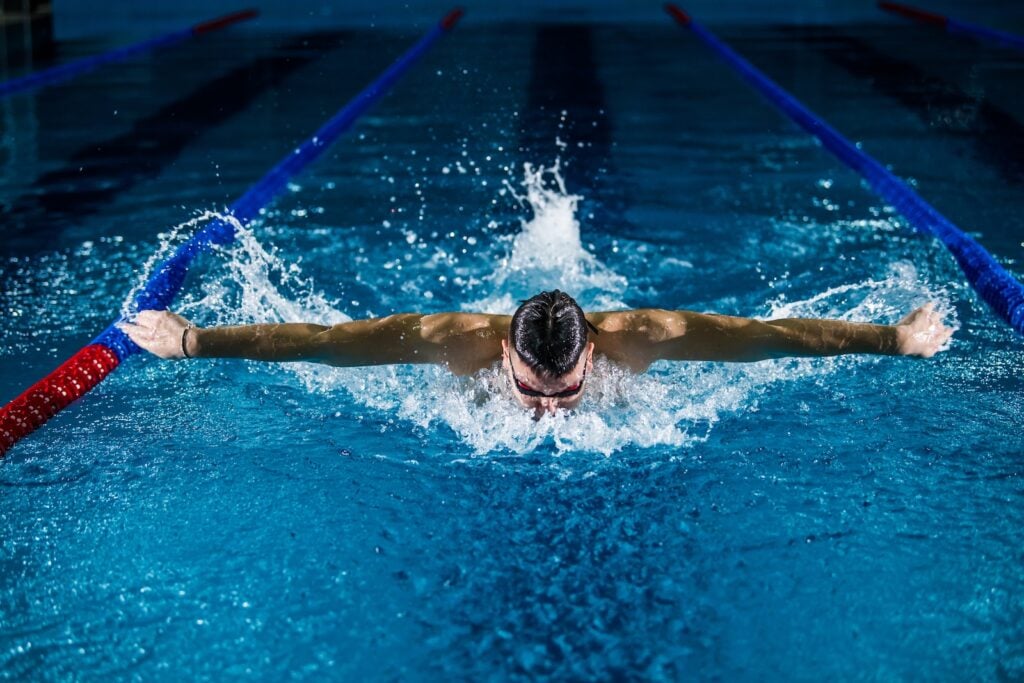 Swimmer performing butterfly stroke in a pool, exemplifying swimming for cardio fitness