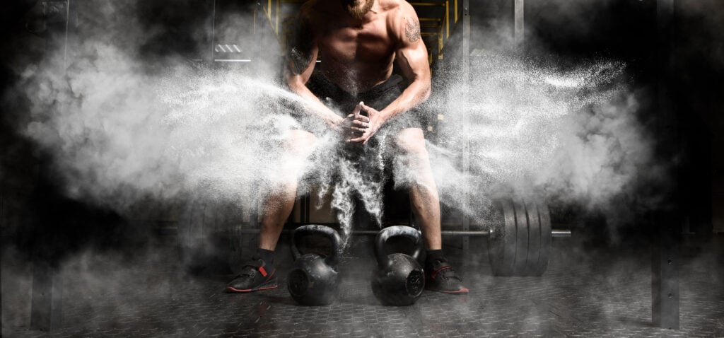 Set of kettlebells on gym floor with dynamic chalk explosion, illustrating intensity and power of kettlebell arm workouts.