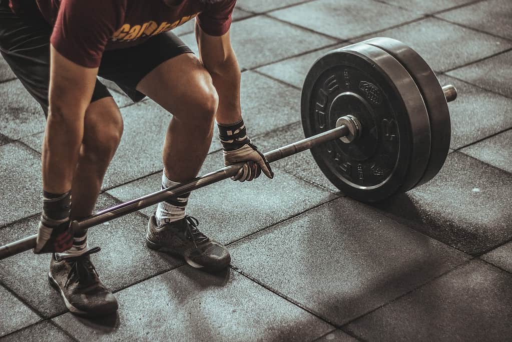 A beginner weightlifter gripping a barbell, ready to perform a squat, symbolizing the importance of understanding weightlifting basics.