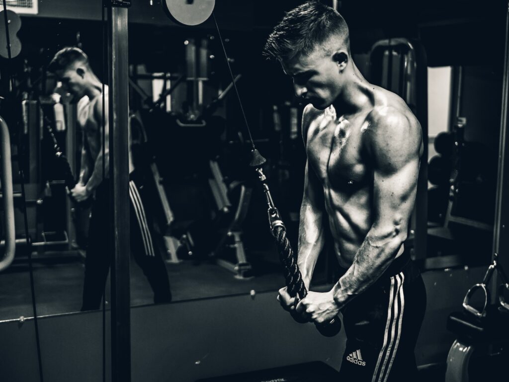 A person performing a tricep pull down exercise on a cable machine, compared to rope tricep push down