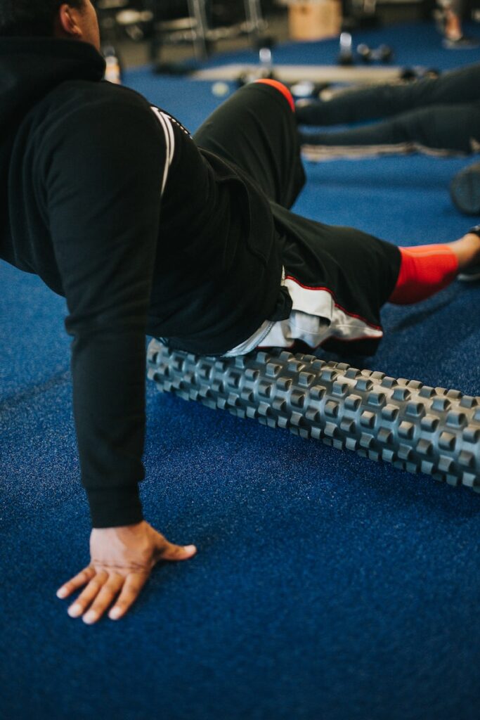 A person skillfully using a foam roller on their hamstring, demonstrating the practice of self-myofascial release.